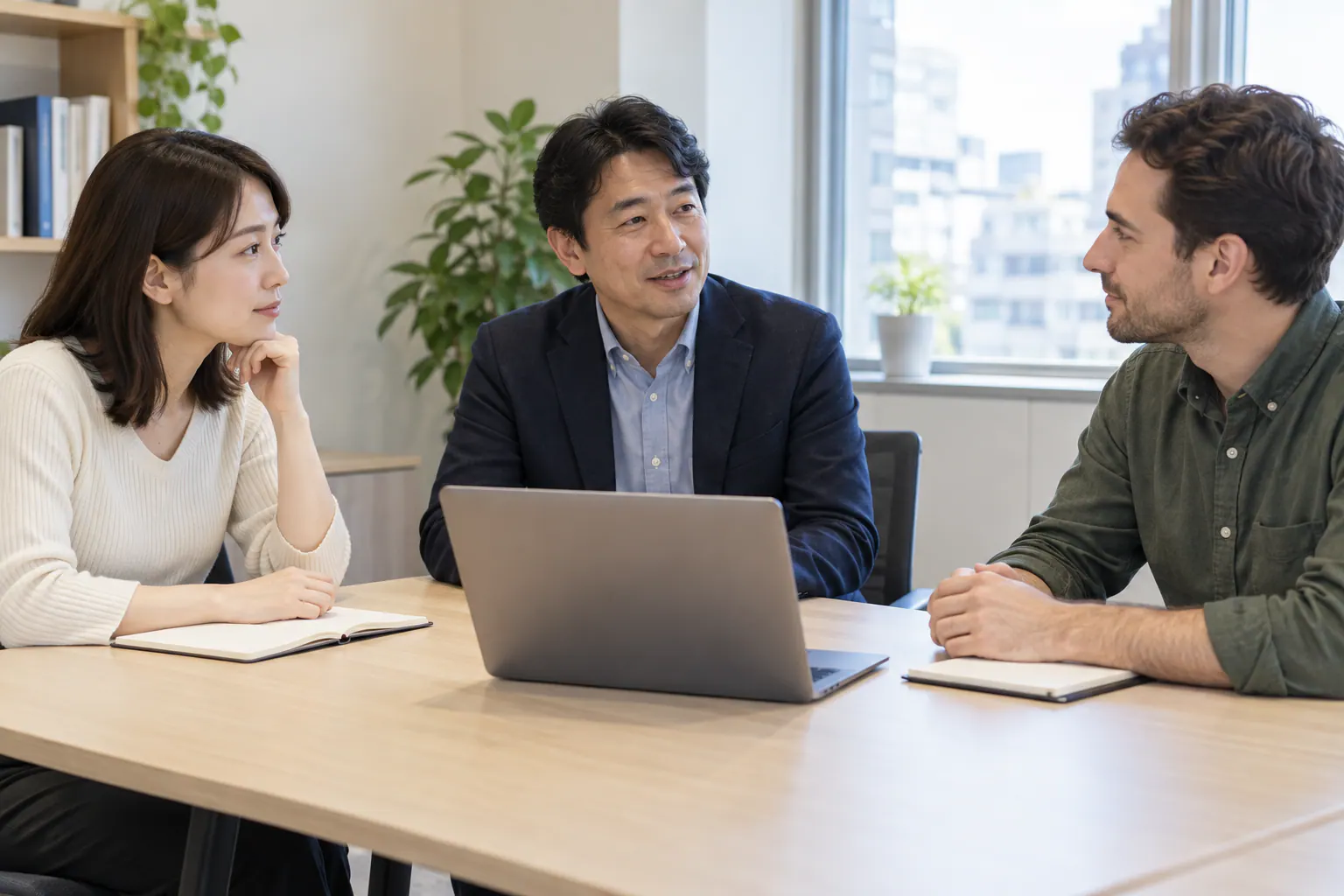 日本語と英語を使う同僚が、机を囲んで仕事の相談をする場面